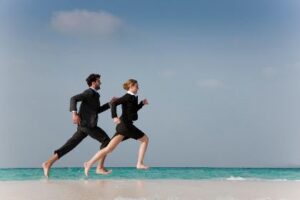 A Couple Running Barefoot on a Beach