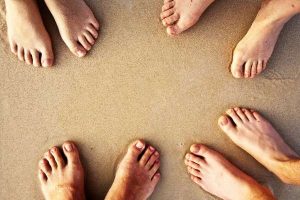 3 pairs of happy feet on the sand of a beach