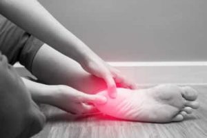 A Woman holding her heel which is highlighted in re