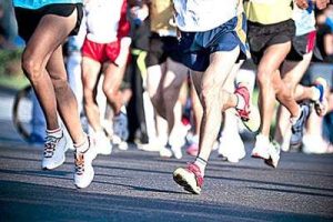 Many runners from the hips down in a road race.