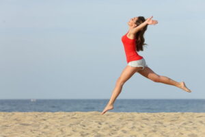Woman Leaping Joyously on Beach