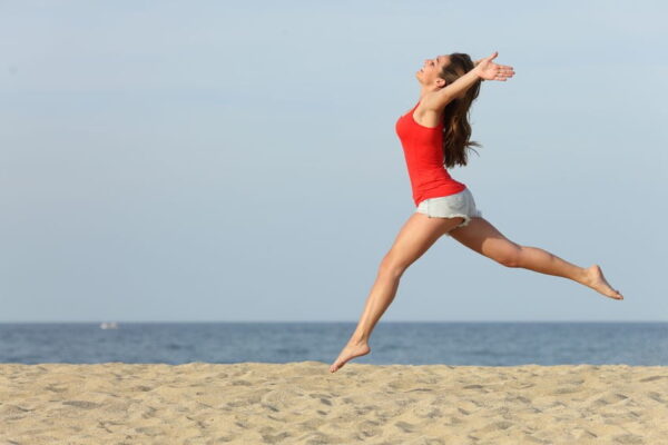 Woman Leaping Joyously on Beach